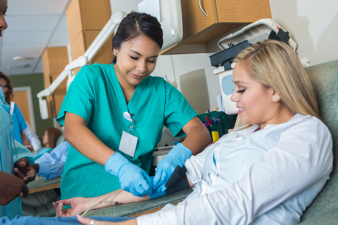 Confident phlebotomist places bandage on blood donor's arm